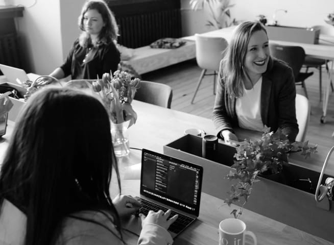 image of 3 women at work desk with purplish tint